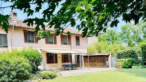 A two-story house with a tiled roof, a covered patio, and a well-maintained lawn. - Garden House, a Quiet Retreat Just 30 Minutes from Milan (Pavia)