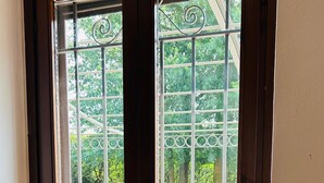 A window with metal bars and a door, overlooking a garden with pink flowers. - Garden House, a Quiet Retreat Just 30 Minutes from Milan (Pavia)