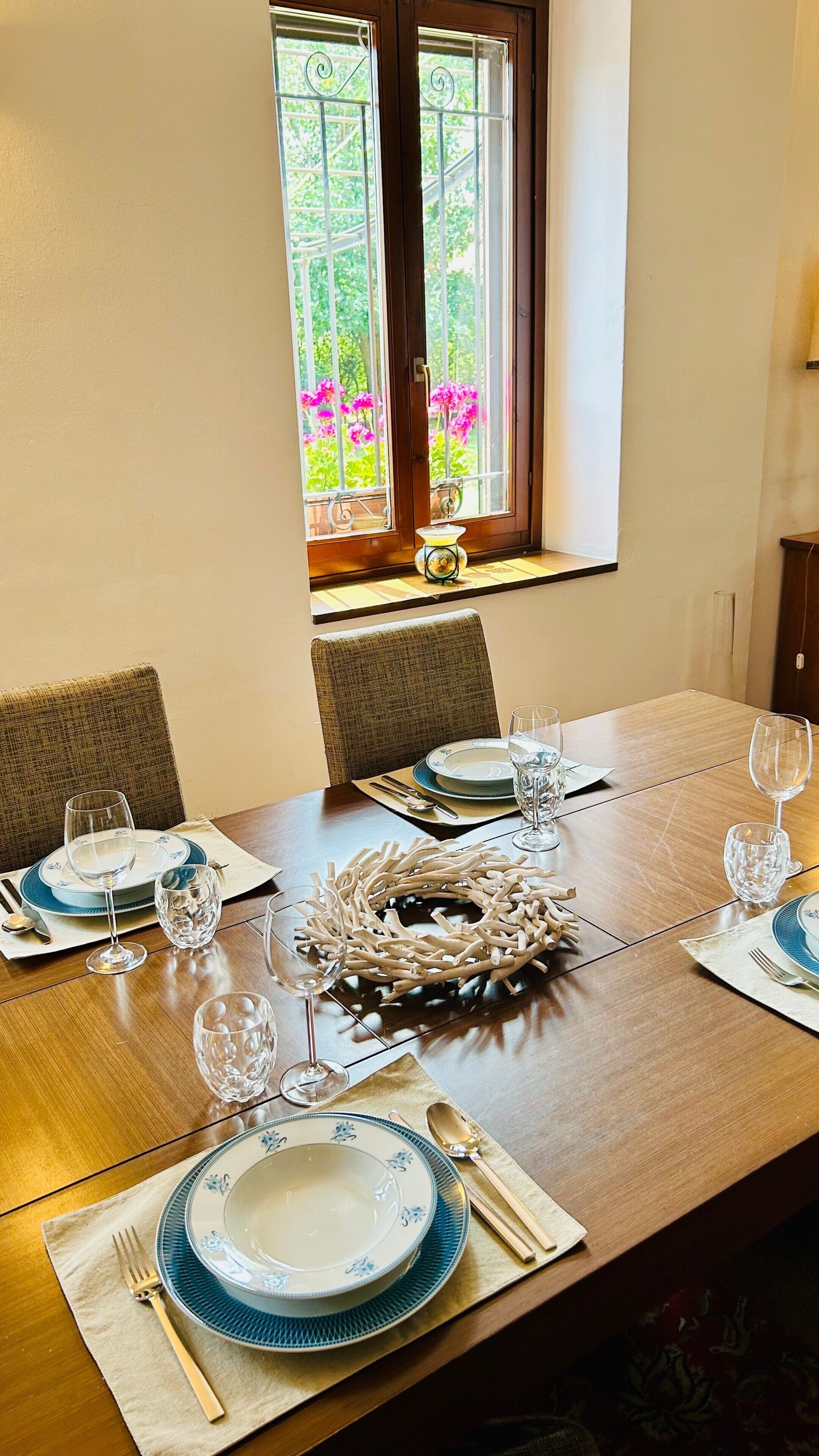 A dining table set with plates, glasses, cutlery, and a decorative centerpiece.