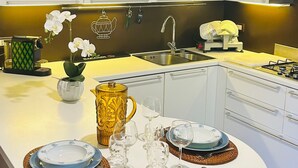 A modern kitchen with white cabinets, a central island with a sink, and a dining area set for four with plates and glasses. - Garden House, a Quiet Retreat Just 30 Minutes from Milan (Pavia)