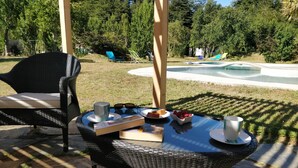 An outdoor patio with a wicker table, chairs, and a book. - Kari Mapu Park (Pucón)