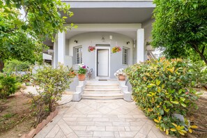 A house with a front porch, steps leading to the door, potted plants, and a garden area. - Magic Garden House 33, near sea & center (Athens)