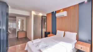 Et moderne hotelværelse med en stor seng, en væg af træpaneler, en aircondition og et lille natbord.