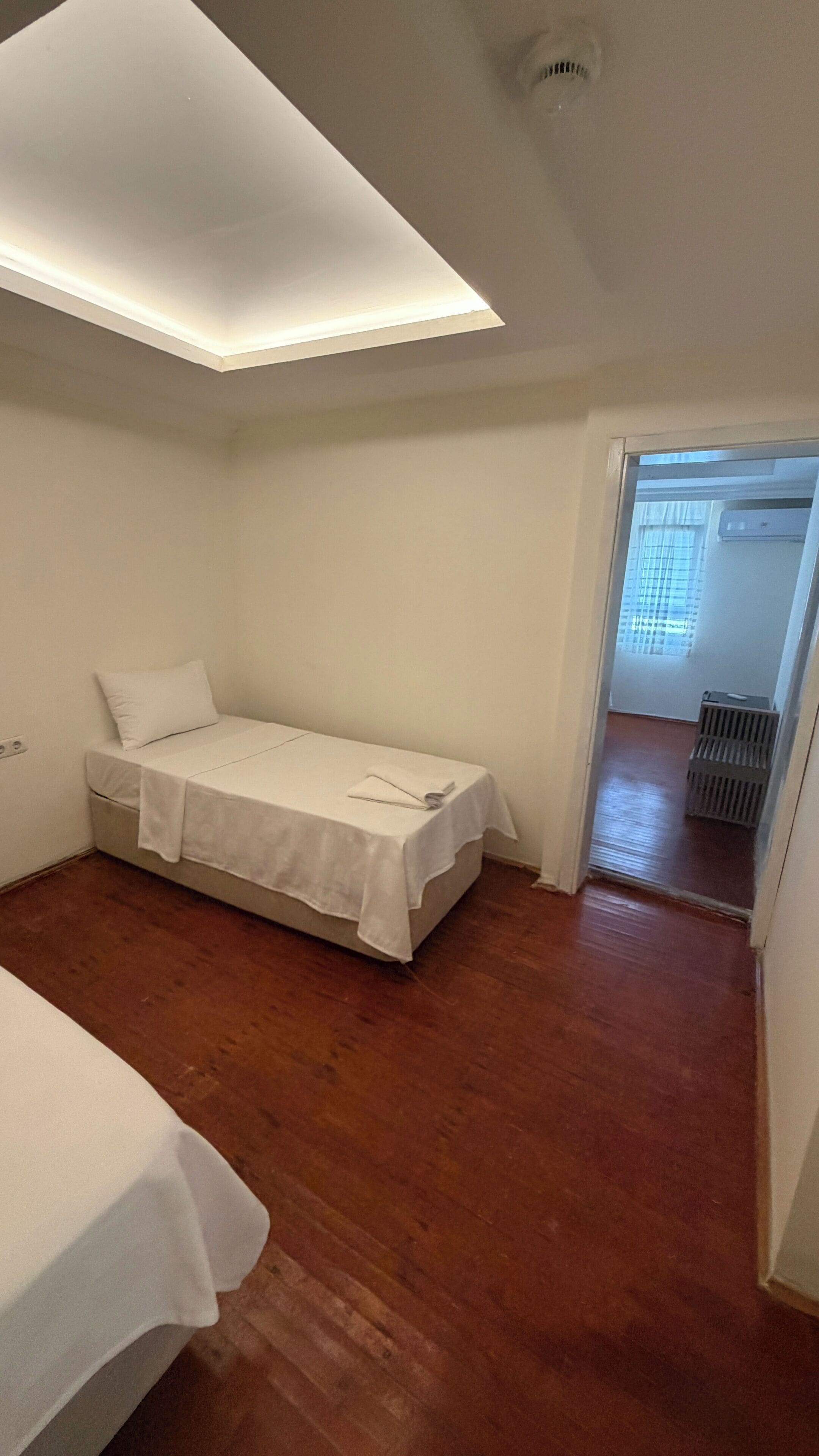 Ein kleines Zimmer mit einem Einzelbett, schrägen Wänden und einer Heizung.