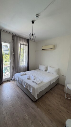 A bedroom with a bed, a ceiling fan, an air conditioning unit, and a view of the outdoors through a window. - Corte Hotel Kaş (Kas)