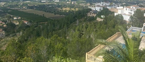 Un pueblo costero con abundante vegetación, un edificio blanco destacado con balcón y vista al mar.