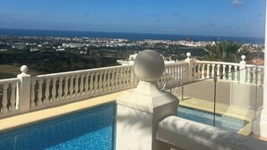 Una piscina con vista despejada a un paisaje urbano y al océano al fondo.