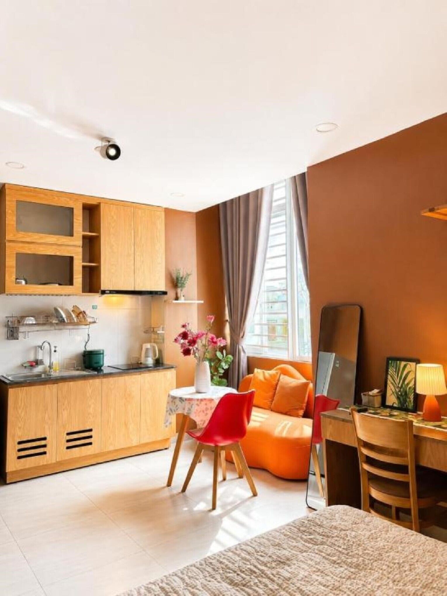 A compact hotel room with a kitchenette, a dining area, a bed, and a large window.