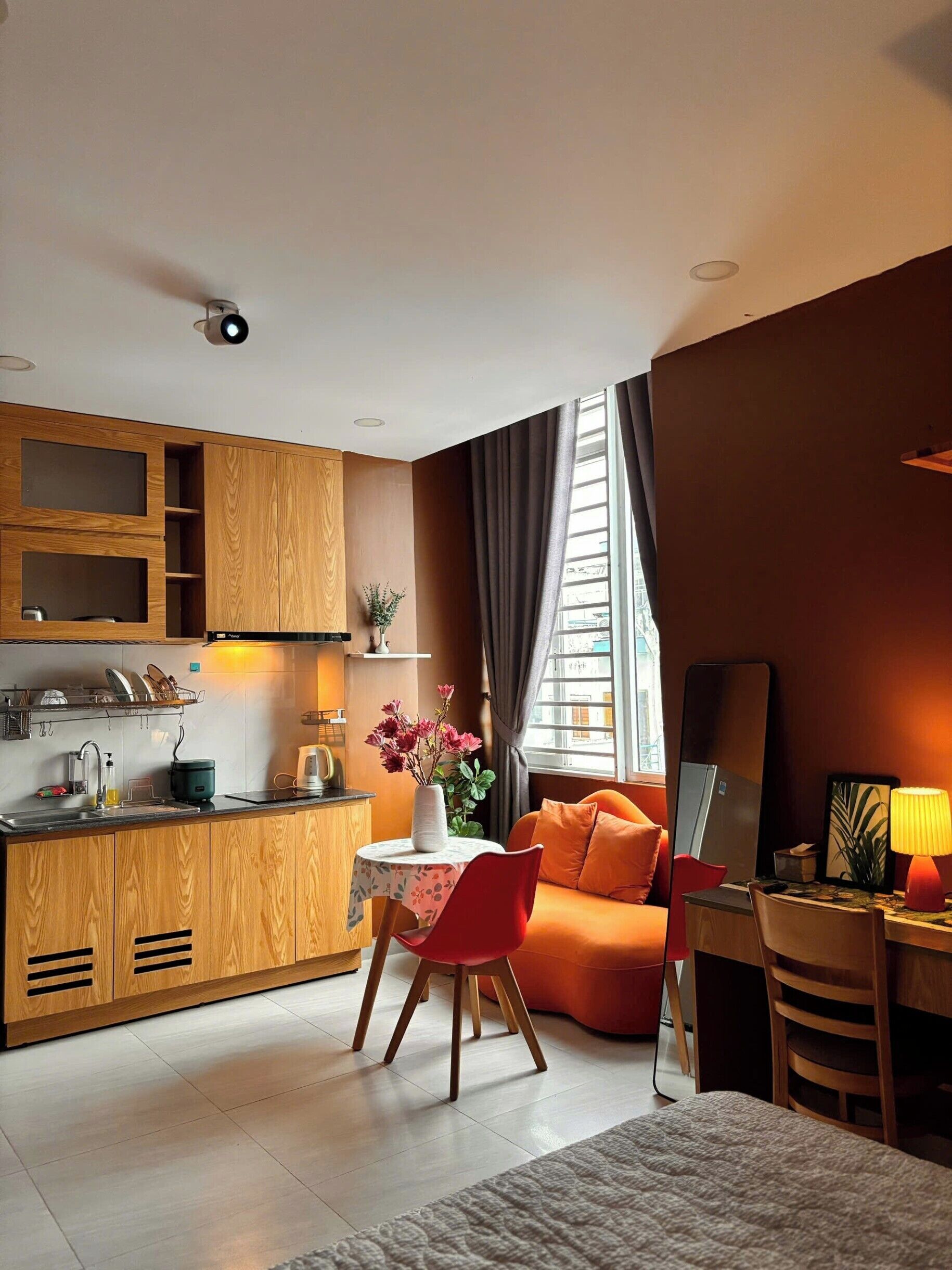 Una cucina moderna con mobili in legno, un'area pranzo con tavolo e sedie, e un angolo salotto accogliente con divano e lampada.