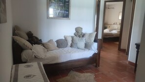 A cozy living room with a sofa, pillows, a teddy bear, and a painting on the wall. - Clos Saint-Véran: Rooms in a Tree-Filled Provençal Mas (Cavaillon)