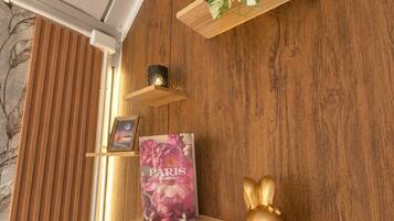 Eine Holzwand mit einem Regal, auf dem ein Buch mit dem Titel 'PARIS CARPEA', eine kleine goldene Hasenfigur und ein Topf mit einem topfpflanze mit gefleckten Blättern stehen.