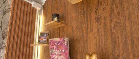 A wooden wall with a shelf holding a book titled 'PARIS CARPEA,' a small golden bunny figurine, and a potted plant with variegated leaves.