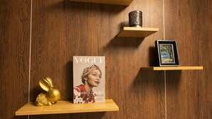 A wooden wall with three shelves, each holding different items: a magazine, a framed picture, and a potted plant. - Near BKK Homestay Airport (Bang Phli)