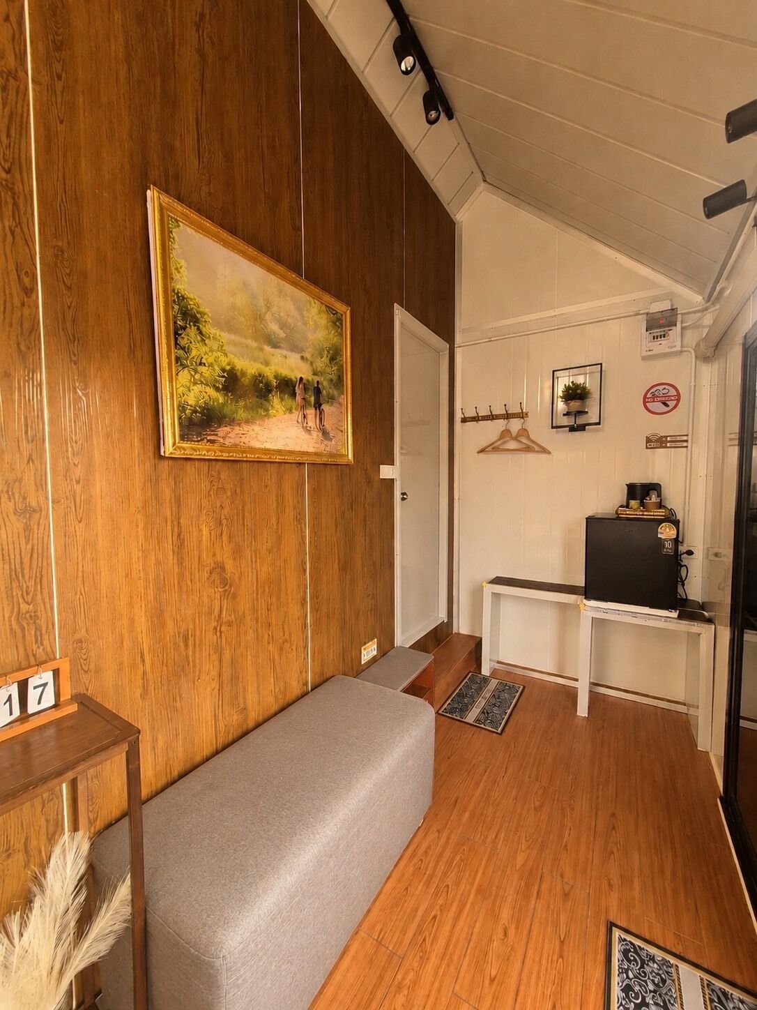 A room with wooden paneling, a painting, a bench, a desk, and a television.