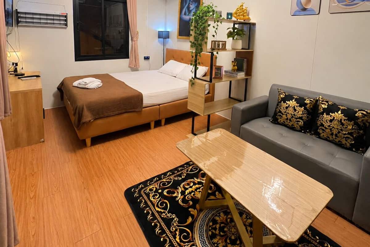 Una habitación de hotel moderna con cama, sofá, escritorio y elementos decorativos como cortinas y cuadros.