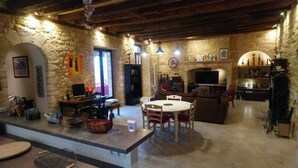 A rustic interior with stone walls, a fireplace, a television, and a dining area. - The chaplain's dwelling (DOMME)