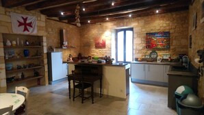 A rustic kitchen with stone walls, a wooden ceiling, and a flag on the wall. - The chaplain's dwelling (DOMME)