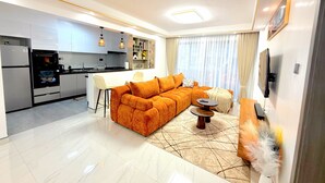 Una sala moderna con un sofá seccional, un comedor y una cocina con isla integrada.