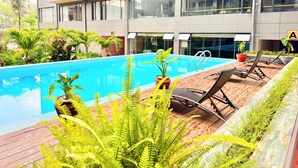 Un hotel moderno con piscina, sillas de descanso y plantas en macetas.