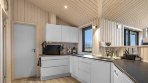 Una cucina moderna con mobili bianchi, pavimento in legno e una finestra che lascia entrare luce naturale.