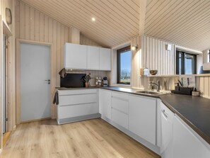 Eine moderne Küche mit weißen Schränken, Holzboden und einem Fenster, das für natürliches Licht sorgt.