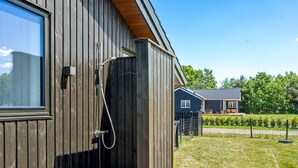 Un edificio moderno con rivestimento in legno, una zona doccia visibile e un prato ben curato.