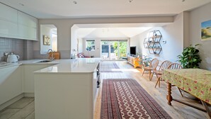 A modern kitchen with a central island, dining area with a table and chairs, and a view of the outdoors.
