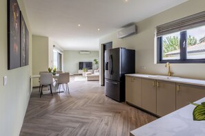 Eine moderne Küche mit Kühlschrank, Essbereich und Blick ins Freie.