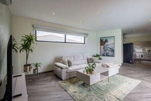 Ein modernes Wohnzimmer mit einer Couch, einem Couchtisch und Topfpflanzen.