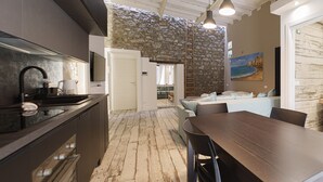 Eine moderne Küche mit Steinwand, ein Essbereich mit Holztisch und -stühlen sowie ein Wohnbereich mit Sofa und einem Gemälde.