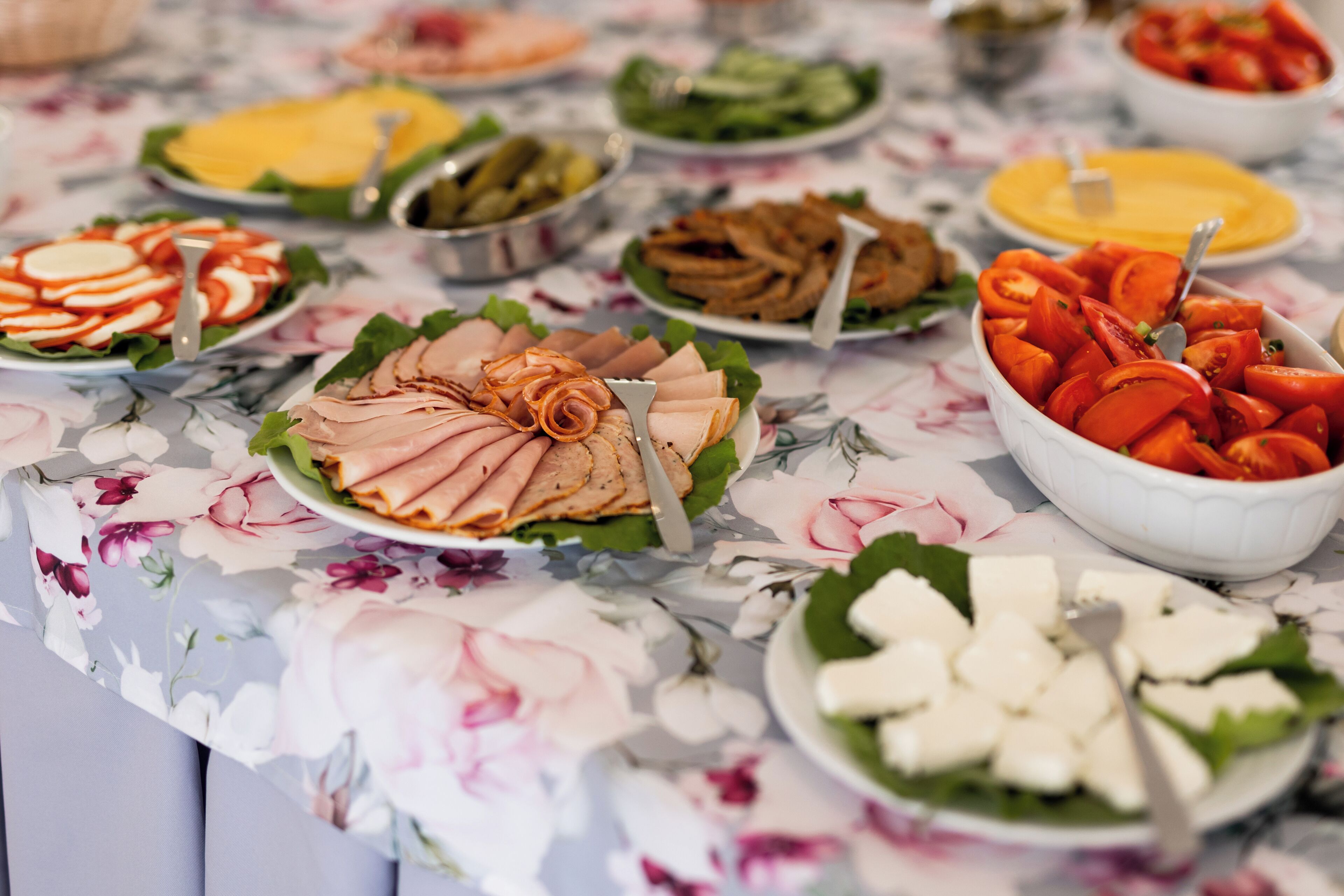 A table with various food items including sliced tomatoes, cheese, and meat.