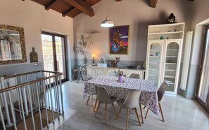 A dining area with a table set for four, a chandelier, a painting, and a white cabinet with glass doors. - La Dimora di Max Bright apt. with Terrace (Riposto)