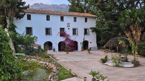 A white building with multiple windows and a courtyard with a fountain and potted plants. - HOTEL MASÍA DE ALTEA  (Altea)