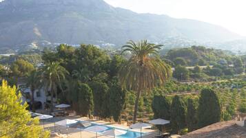 Un resort con piscina, sillas de descanso y sombrillas.