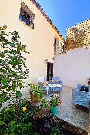 A courtyard with a white building, a small table with chairs, and potted plants. - HOTEL MASÍA DE ALTEA  (Altea)