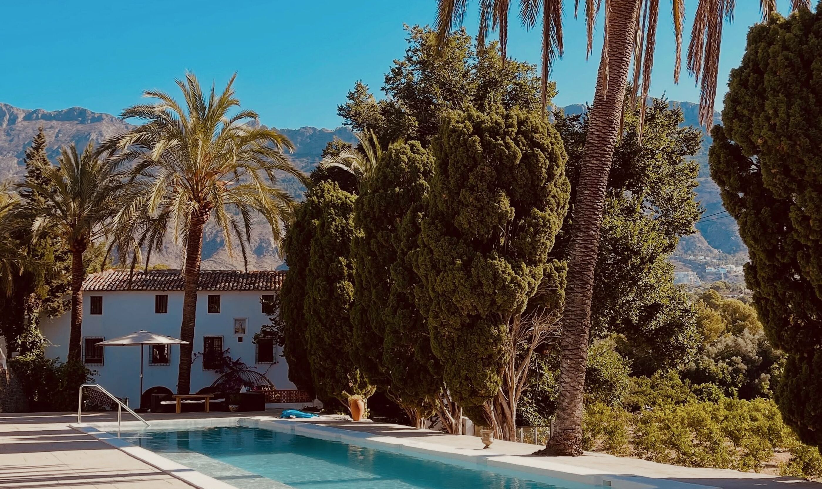 Una piscina al aire libre, sombrillas, tumbonas