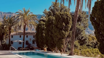 Una piscina al aire libre, sombrillas, tumbonas