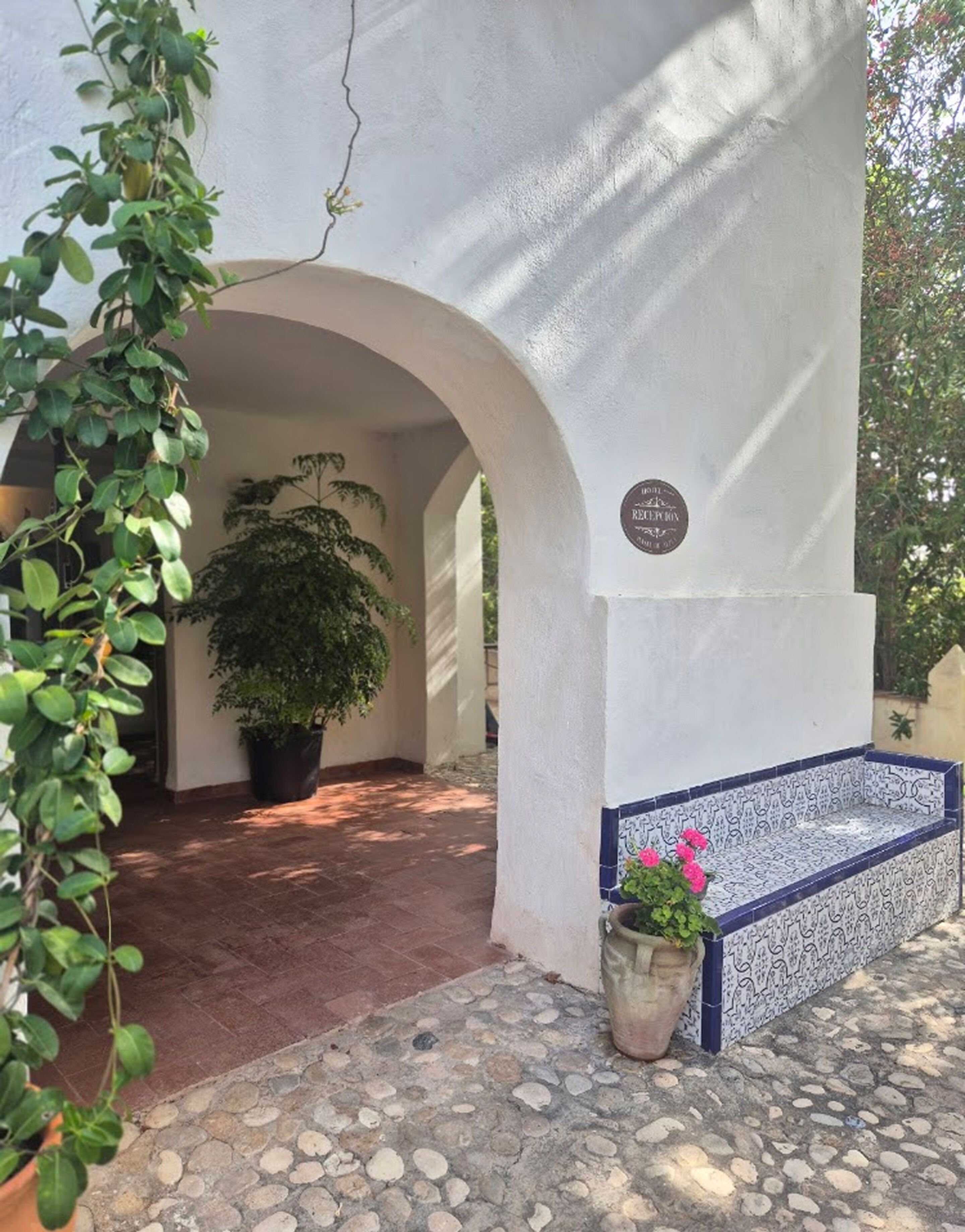 A building with a white exterior, a reception area, and a tiled bench.