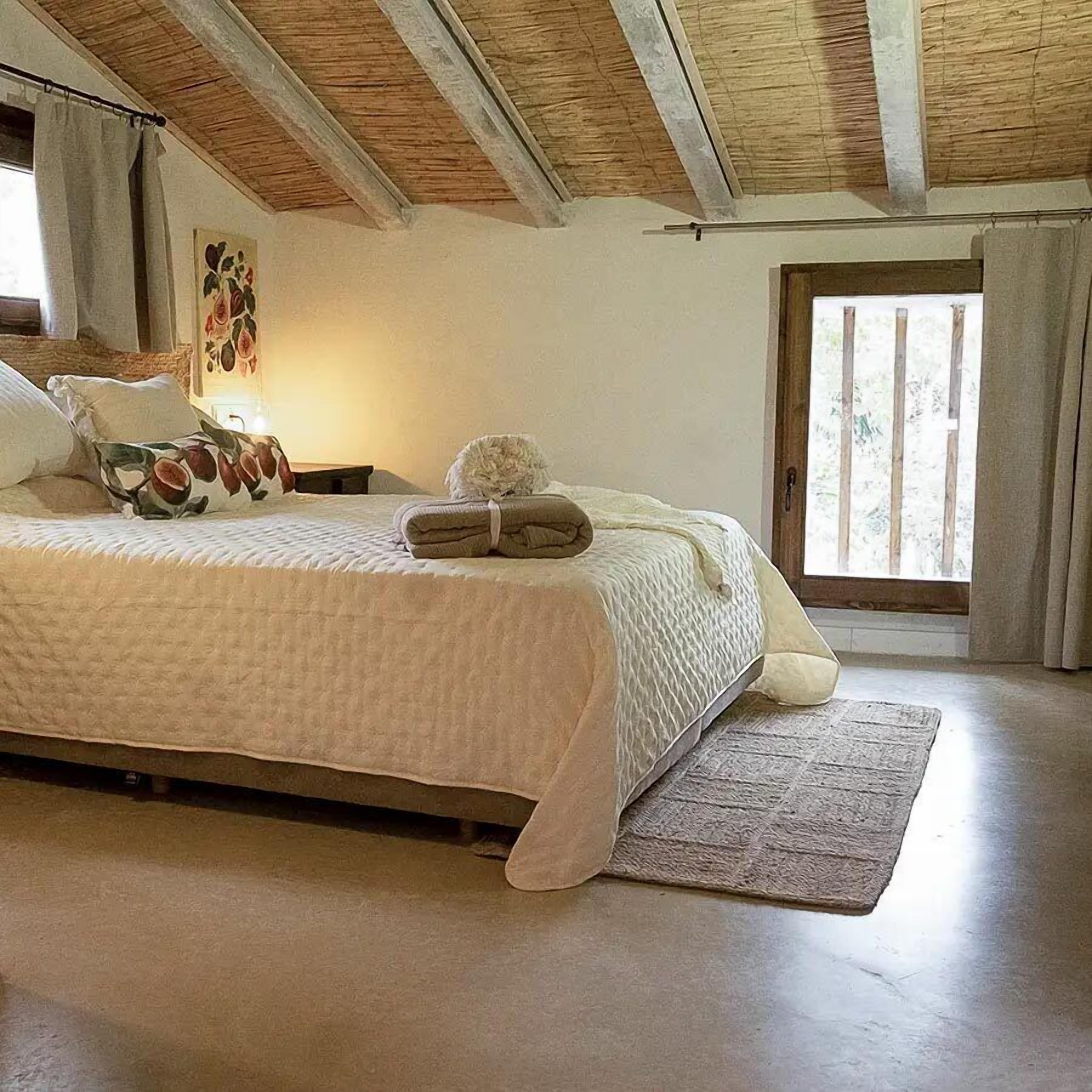 A bedroom with a bed, a nightstand, a window, and a door.