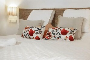 A bed with white bedding, two decorative pillows with a floral pattern, and a wall-mounted lamp. - HOTEL MASÍA DE ALTEA  (Altea)