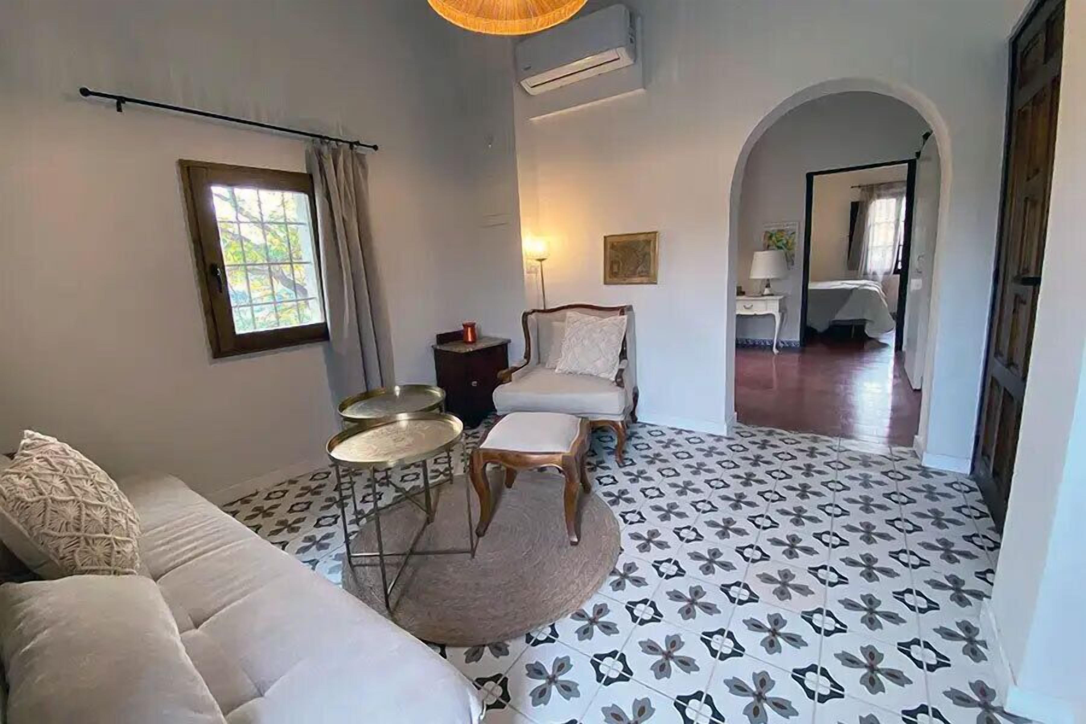 A room with a sofa, a round table, a chair, and a patterned floor.