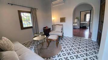 A room with a sofa, a round table, a chair, and a patterned floor.