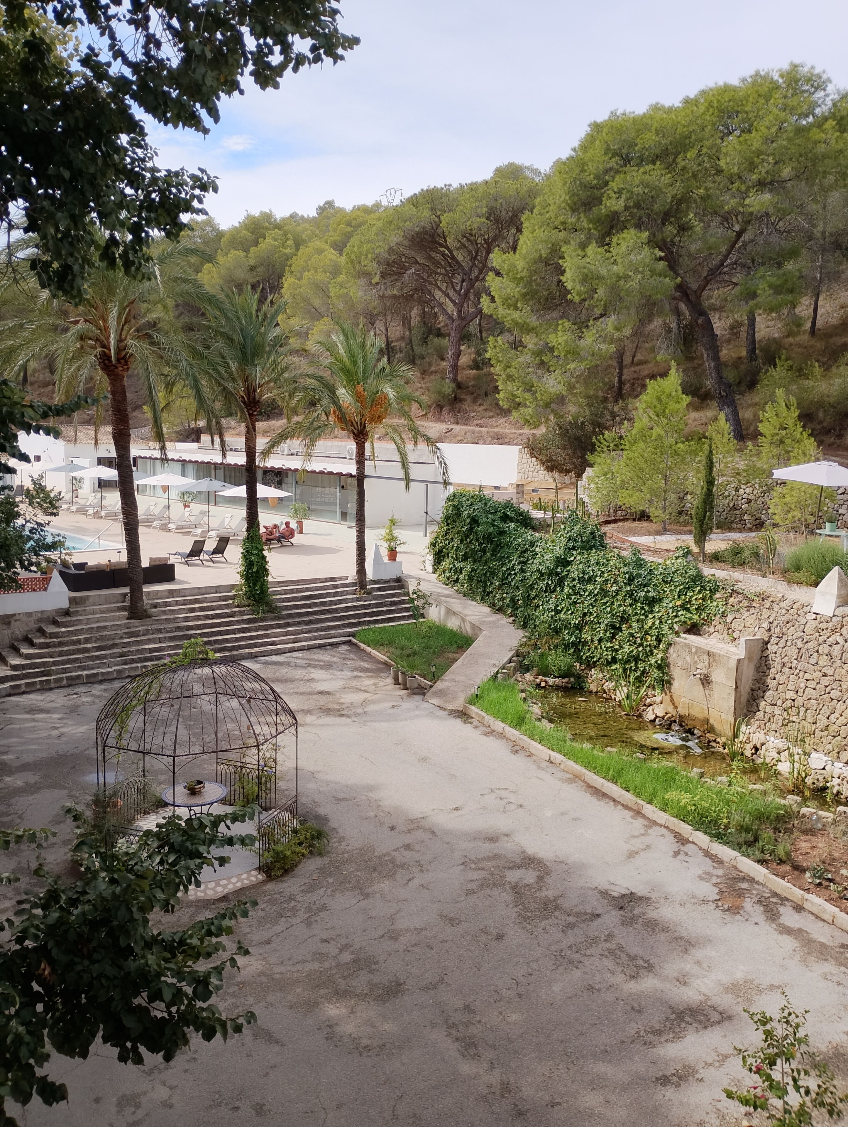 Un resort con mesas al aire libre, piscina y jardín.