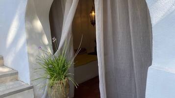 Un arco de entrada con una cortina, una planta en maceta y una pequeña mesa con flores.