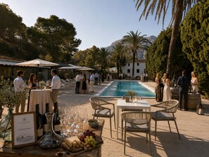 An outdoor pool area with tables and chairs, surrounded by trees and a mountain backdrop. - HOTEL MASÍA DE ALTEA  (Altea)