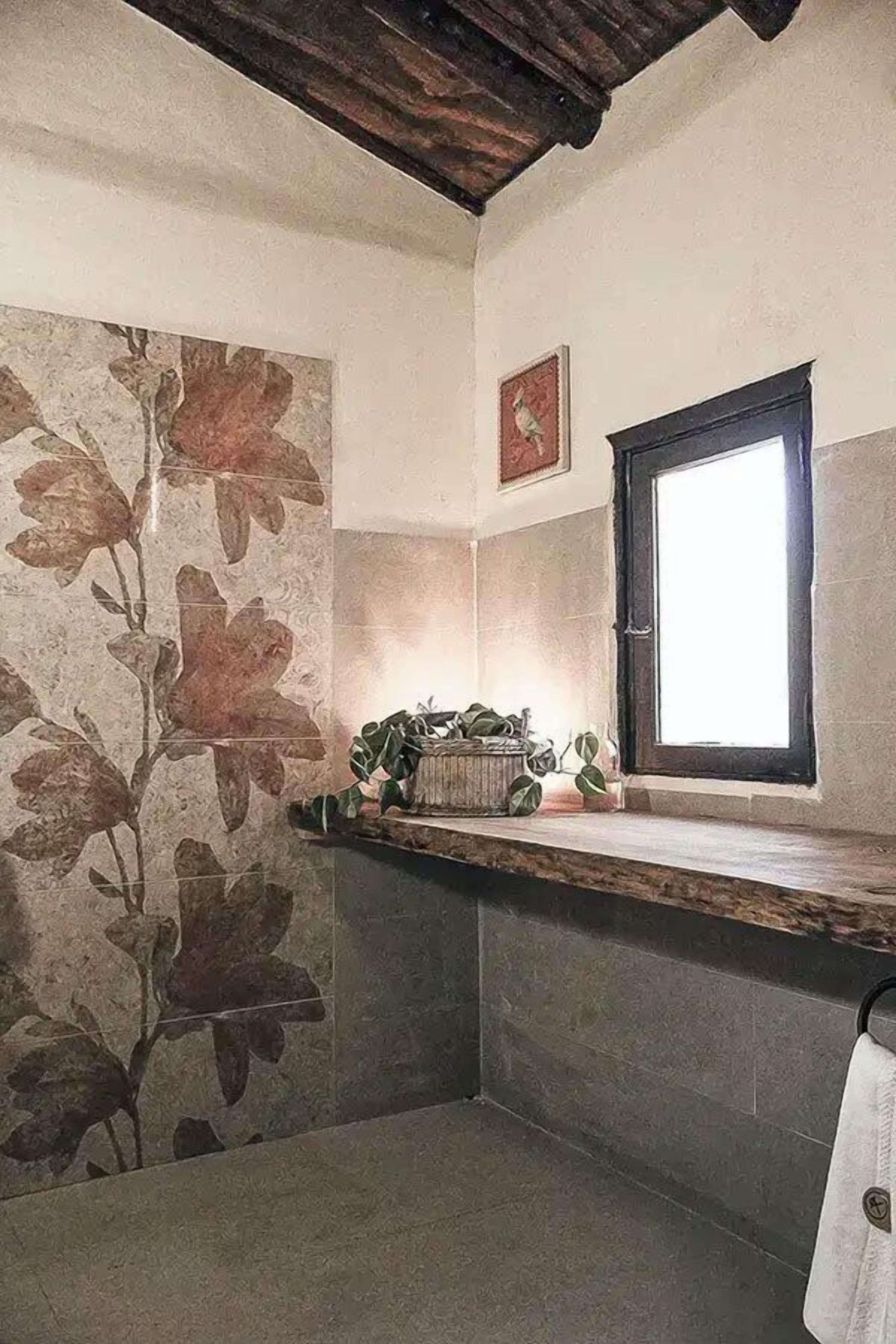 Un baño con pared de piedra, una ventana y un perchero.