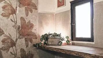 Un baño con pared de piedra, una ventana y un perchero.