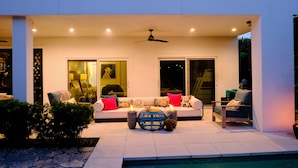 An outdoor seating area with a white sofa, two chairs, a round table, and a ceiling fan. - Luxury Naples Private Retreat w/Resort Pool + Gym (Naples)