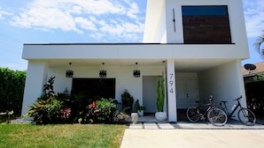 A modern two-story house with a garage, a driveway, and a front yard with various plants. - Luxury Naples Private Retreat w/Resort Pool + Gym (Naples)