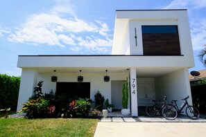 Ein modernes, zweistöckiges Haus mit Garage, Auffahrt und Vorgarten mit verschiedenen Pflanzen.